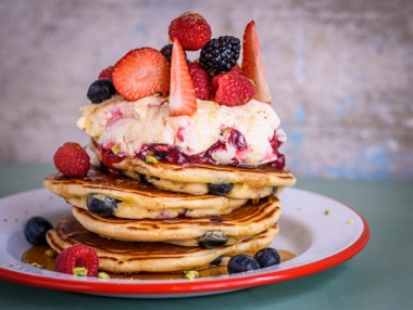 Large stack of pancakes with fresh berries and cream at The Breakfast Club