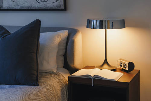 A lamp and a book beside a bed