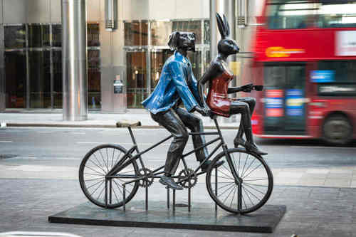 A sculpture of a dog and a bunny riding a bicycle